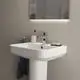 Waschtisch von Ideal Standard mit einem quadratischen Becken, Wasserhahn, Seifenschale und Zahnbürstenhalter. Helle Wand im Hintergrund, Handtuch hängt seitlich.